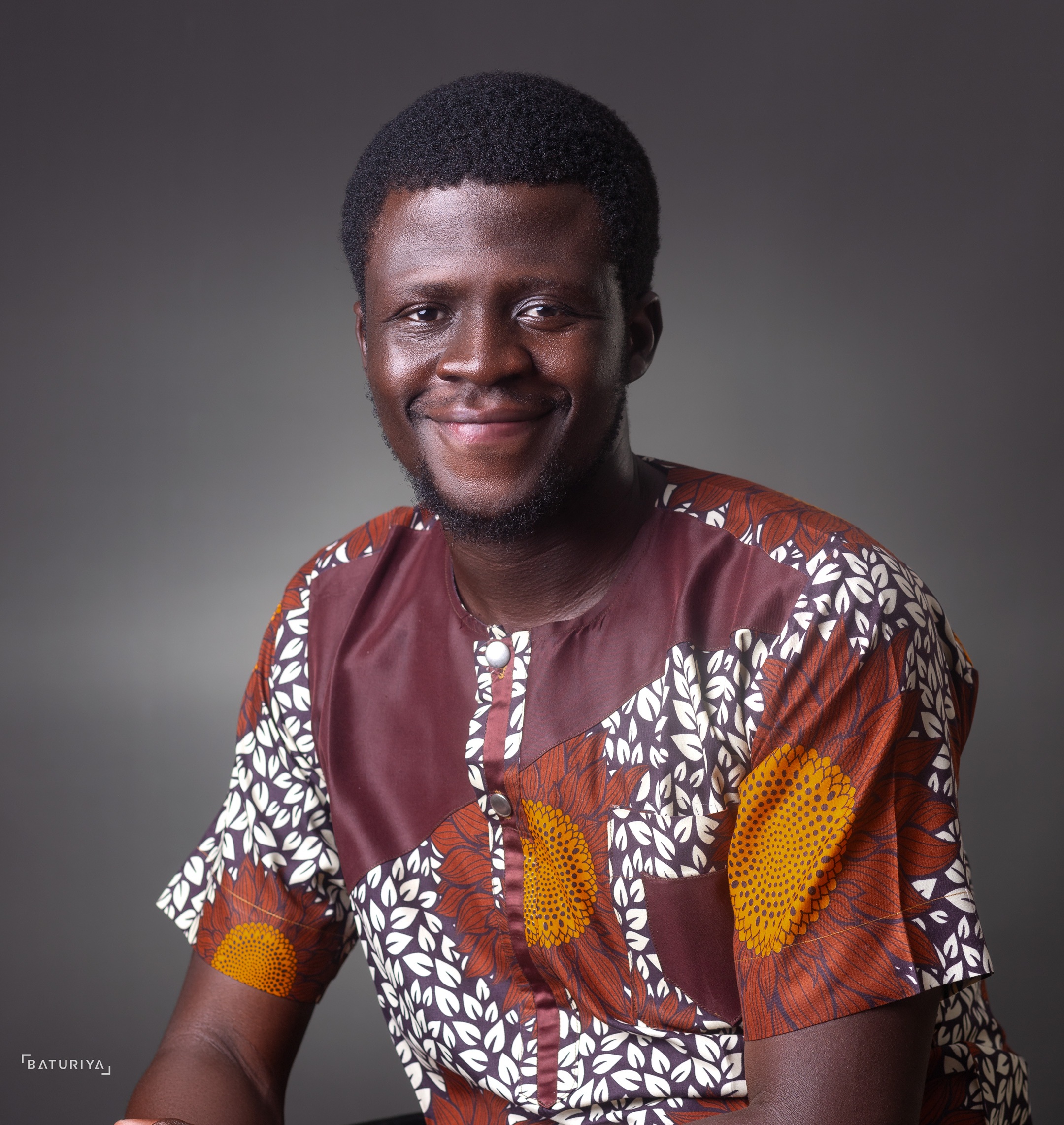 Portrait of Olúwafúnmitọ́ smiling, wearing a patterned shirt